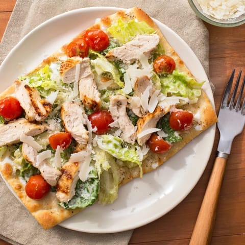 Golden-brown Caesar Chicken Flatbread with grilled chicken slices, crisp romaine, Parmesan, and creamy dressing.