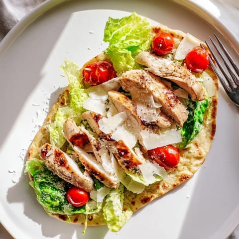 A close-up of Caesar Chicken Flatbread topped with fresh romaine, cherry tomatoes, and shaved Parmesan.
