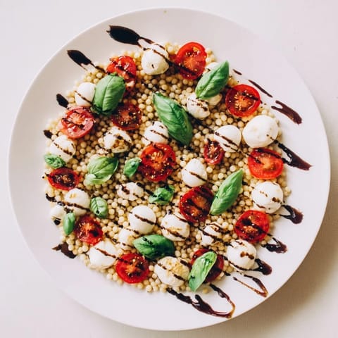 Chilled Caprese Couscous Salad served with a drizzle of balsamic glaze, perfect for summer picnics.