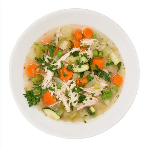 A steaming bowl of Spring Garden Chicken Soup showcases tender shredded chicken, vibrant green peas, and fresh parsley garnish.