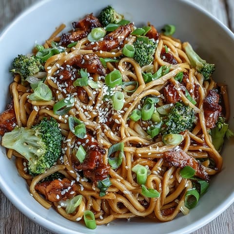 A steaming bowl of Asian teriyaki noodle bowl with tender egg noodles and crisp broccoli in savory-sweet sauce.