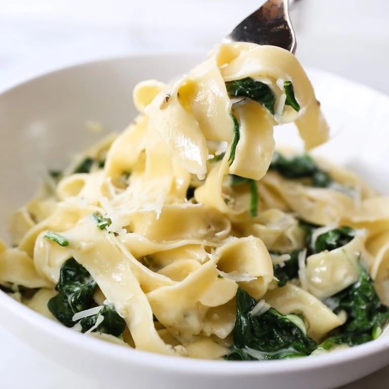 Close-up of Creamy Spinach Garlic Noodles showing tender egg noodles coated in silky garlic cream sauce flecked with spinach.