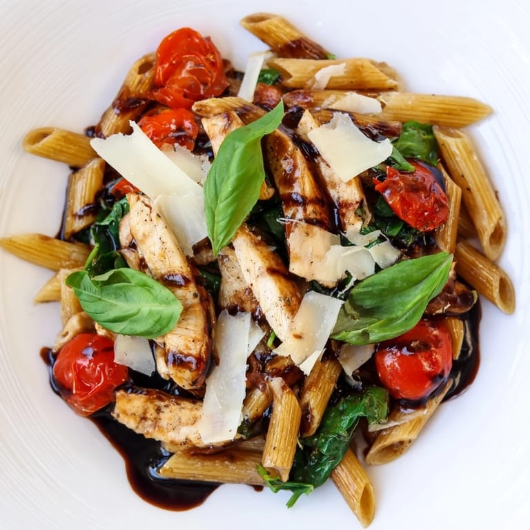 A family-style platter of Balsamic Glazed Chicken Pasta garnished with fresh basil leaves and grated Parmesan, perfect for an easy Italian-inspired weeknight dinner for four.