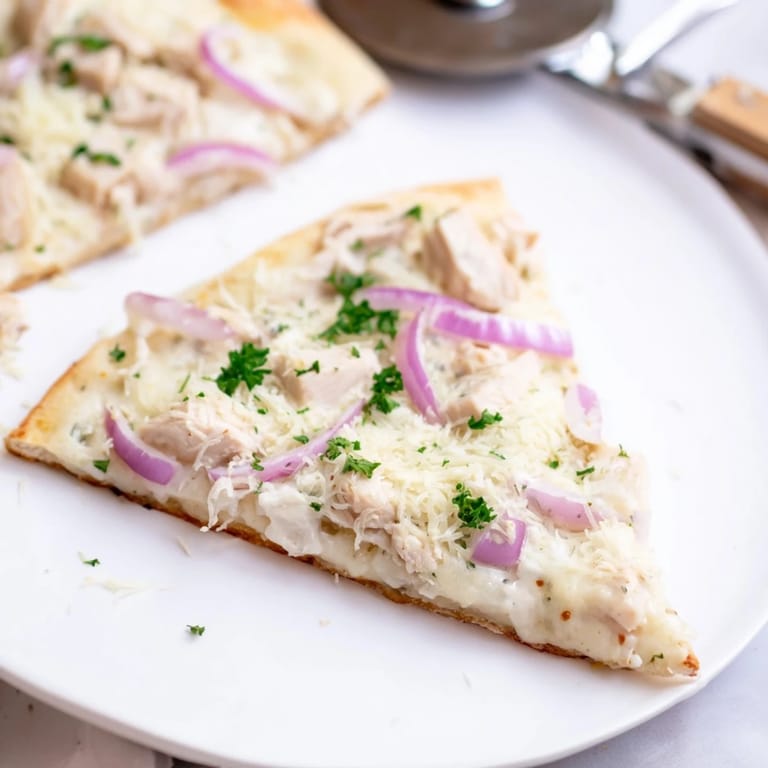 Freshly baked Chicken Alfredo Pizza sits on a pizza stone, steam rising, ready to serve with a side salad.