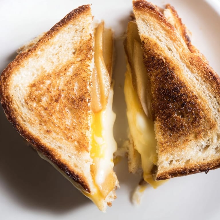 Close-up of Smoked Gouda & Apple Grilled Cheese on a wooden board, highlighting gooey cheese and thinly sliced tart apple.