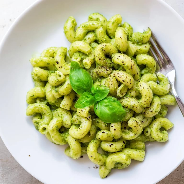 A vibrant bowl of Creamy Avocado Pesto Mac tossed with tender pasta, featuring a bright green, luscious homemade avocado pesto sauce.  