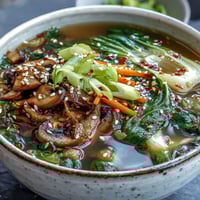 A warm bowl of Miso Ginger Winter Soup with wilted greens and tender vegetables, served as a nourishing vegan meal.