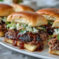 Juicy BBQ brisket sliders stacked high with smoky meat and creamy coleslaw on soft slider buns.  